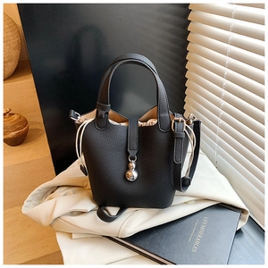 Detalle del bolso de cubo en cuero negro con colgante plateado y forro de cordón