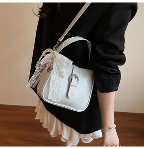 Detail of chic beige bucket bag featuring elegant lace bow and layered pearl chain
