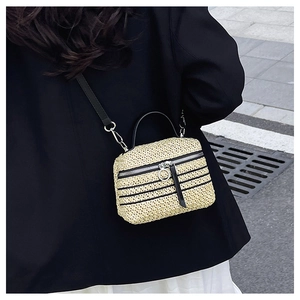 Détail du sac à bandoulière en paille tissé main avec rayures noires et lanière en cuir