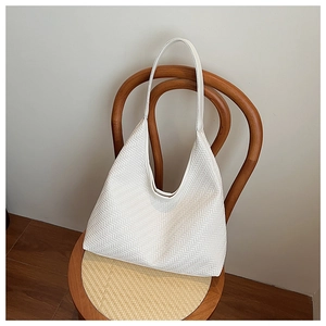 Detail of the white woven texture on a vintage hobo shoulder bag hanging on a chair
