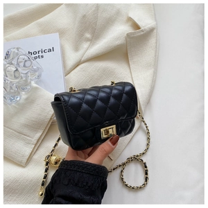 Detail of black quilted crossbody bag with gold chain strap and metal ball accessory