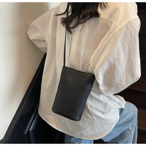 Lifestyle shot showing the back view of a black bucket bag with lychee texture and strap