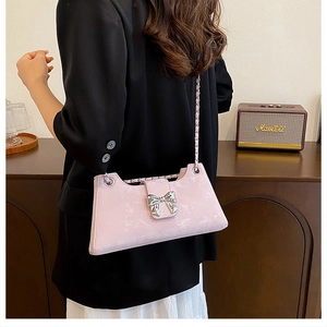 Détail d'un petit sac rose avec nœud argenté et fine bandoulière en chaîne métal