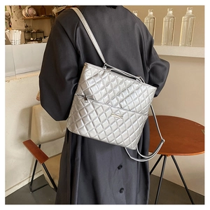 Detail of silver quilted tote bag with metallic finish shown on model in cafe setting