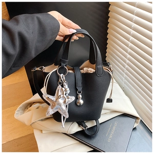 Detalle de bolso bucket de cuero negro con colgante de estrella y bolsa interior con cordón