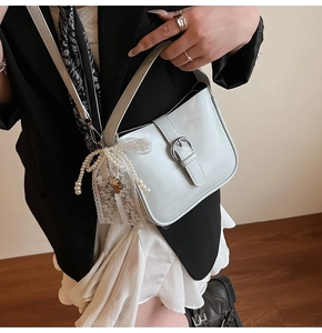 Detail view of stylish bucket bag featuring pearl charms and a lace bow decoration