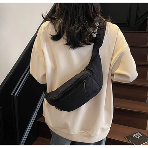 Detail of black crossbody bag with multiple zippers shown on a model on stairs
