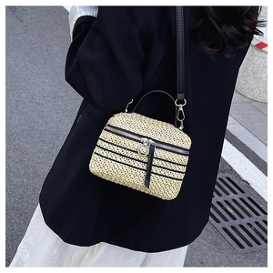 Détail d'un sac en paille tissé à la main avec rayures noires et zip en anneau métallique