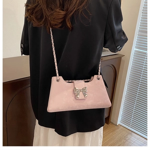 Détail du sac baguette rose avec nœud argenté et bandoulière en chaîne porté