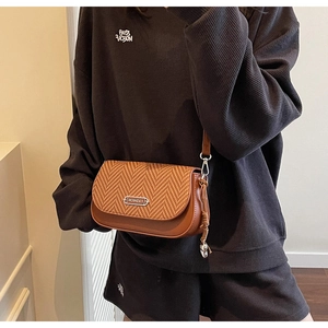 Vue détaillée du sac bandoulière marron en cuir et tissé avec emblème métallique