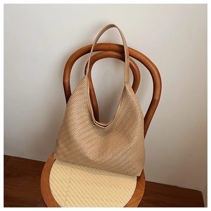 Detail view of beige woven tote bag hanging on a vintage wooden chair for summer travel
