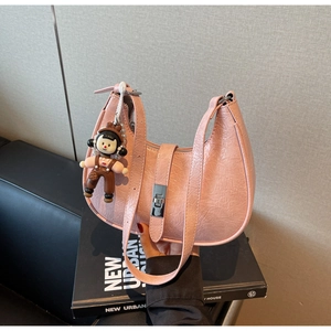 Detail of pink croissant bag with pleated texture, silver buckle and cartoon charm