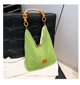 Detail of green crochet tote bag with round wooden bead handle and orange leather patch