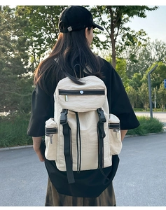 Outdoor close-up of a cream hiking backpack with black buckle straps and side pockets