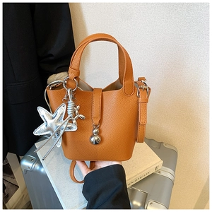 Detalle del bolso tipo cubo naranja con dijes plateados de estrella de mar y perro