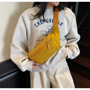 Close-up of bright yellow nylon crossbody bag featuring adjustable strap and logo