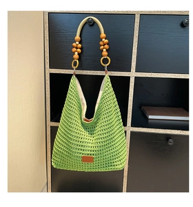 Detail of green hollow knit tote bag with wood bead strap and leather patch