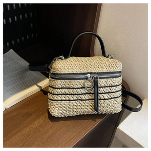 Détail d'un sac boîte en paille tressée à la main avec poignée en cuir noir
