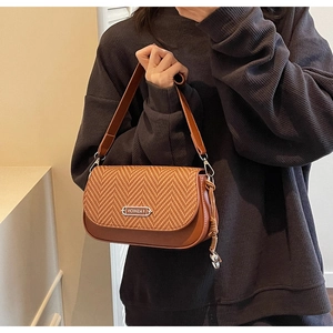Détail d'un sac à bandoulière en cuir marron avec rabat tressé et boucle métallique