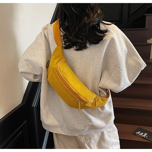 Detailed view of yellow nylon crossbody chest bag with zipper cords and black side label