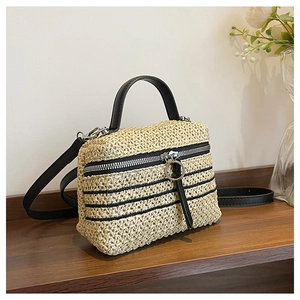 Détail du sac à bandoulière en paille tressé avec rayures noires et lanière en cuir