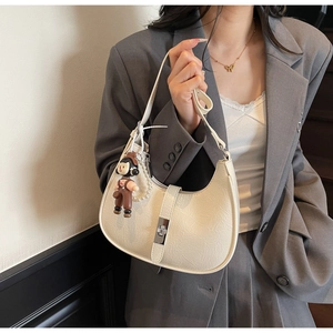 Detail of cream hobo bag with cracked leather texture, silver buckle and pearl chain charm