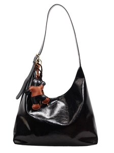 Fashionable black glossy hobo tote bag with a cartoon doll charm on white background