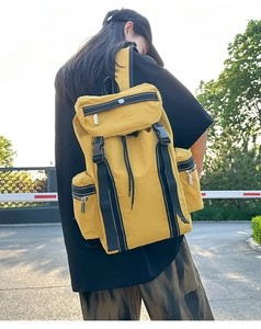 Side view of bright yellow tactical nylon backpack with buckles on a female model outdoors
