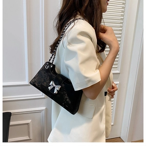 Détail du nœud en métal argenté sur un sac bandoulière noir avec sangle en chaîne