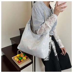 Détails de broderies papillons roses et motifs de volutes sur un sac cabas bleu clair