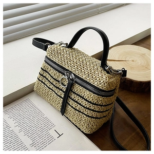 Détail du sac à main en paille tissée avec garniture en cuir noir et fermeture éclair