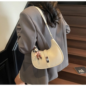 Detail of off-white crescent bag with silver twist lock and decorative pearl chain