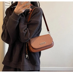 Détail du sac bandoulière marron avec texture tissée et plaque en métal argenté