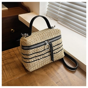 Détail d'un sac boîte tissé beige avec lanières en cuir noir et double zip métallique