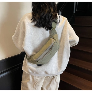 Close-up of military green nylon chest bag with brand logo and wide shoulder strap