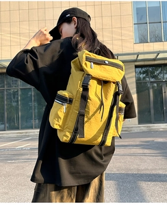 Outdoor side view of a vibrant yellow hiking backpack with nylon texture and black buckles
