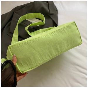 Gros plan d'un sac à bandoulière plissé vert citron avec large sangle et coutures fines