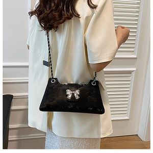 Détail du sac baguette en velours noir avec boucle à nœud argenté sur mannequin