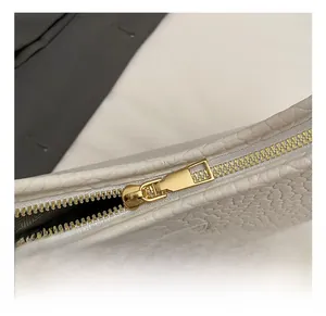 Close-up of premium gold-toned zipper hardware and textured white leather detail