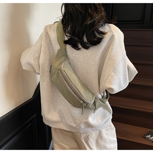 Detail showing back view of light green nylon crossbody chest bag on model