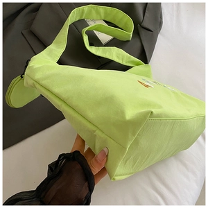 Détail du cabas en nylon vert néon avec broderie Amide et petit porte-monnaie rond attaché