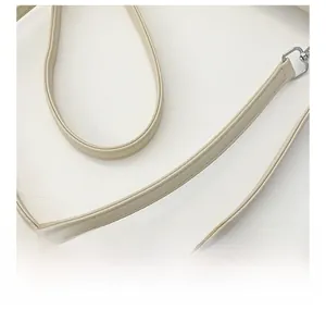 Close-up of creamy white faux leather shoulder strap with fine stitching and silver hook