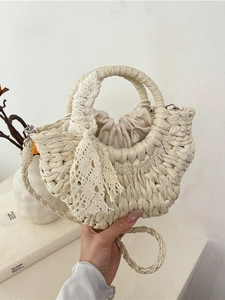 Off-white semi-circular woven straw handbag with lace bow and drawstring closure
