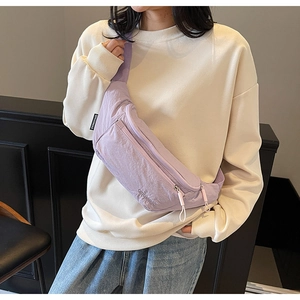 Detailed view of light purple nylon belt bag with zippers shown on a casual outfit