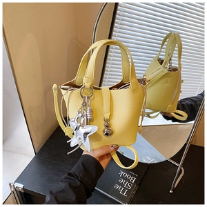 Detalle del bolso tipo cubo amarillo con textura de grano y colgante de estrella de mar
