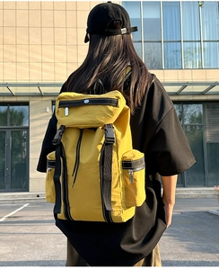 Detailed back view of a ginger yellow waterproof travel backpack with adjustable straps