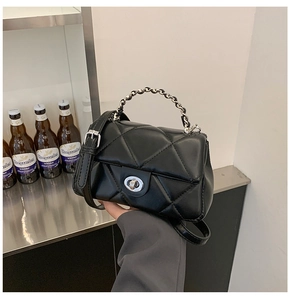 Close-up of black quilted leather handbag featuring silver twist lock and chain strap