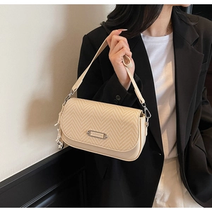 Détail du sac sous le bras en paille tisse et similicuir beige avec plaque argentée