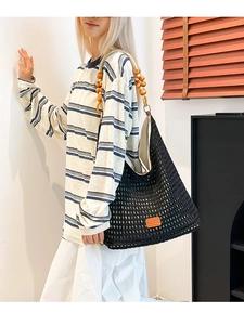 Large black hollow knit crochet tote bag with wooden bead straps and orange leather tag