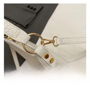 Close-up of premium gold hardware hook and white textured leather on shoulder bag